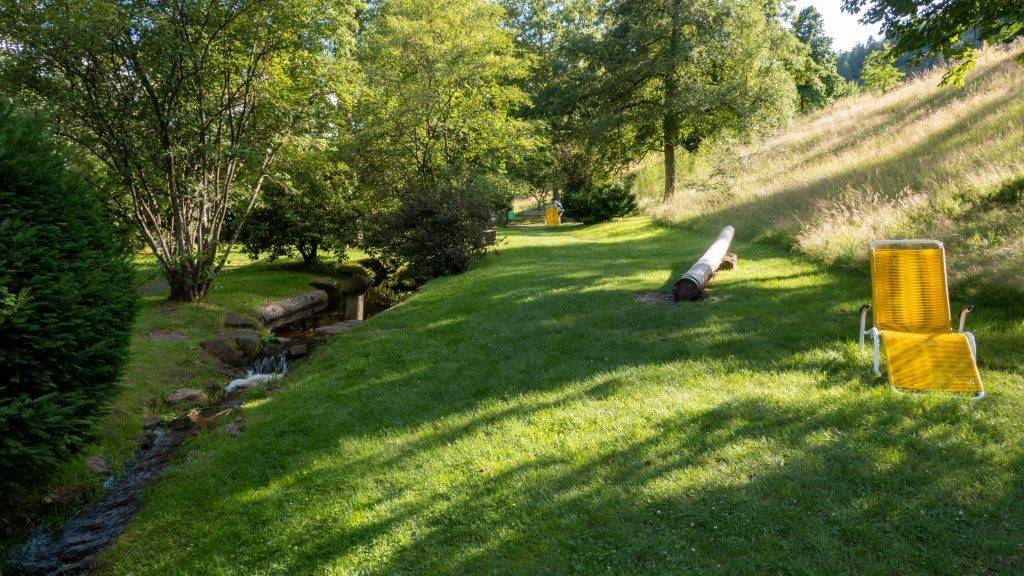 Gelbe Liegestühle auf der Liegewiese im Kurpark Bad Wildbad, am Rand läuft der kleine Bach vorbei