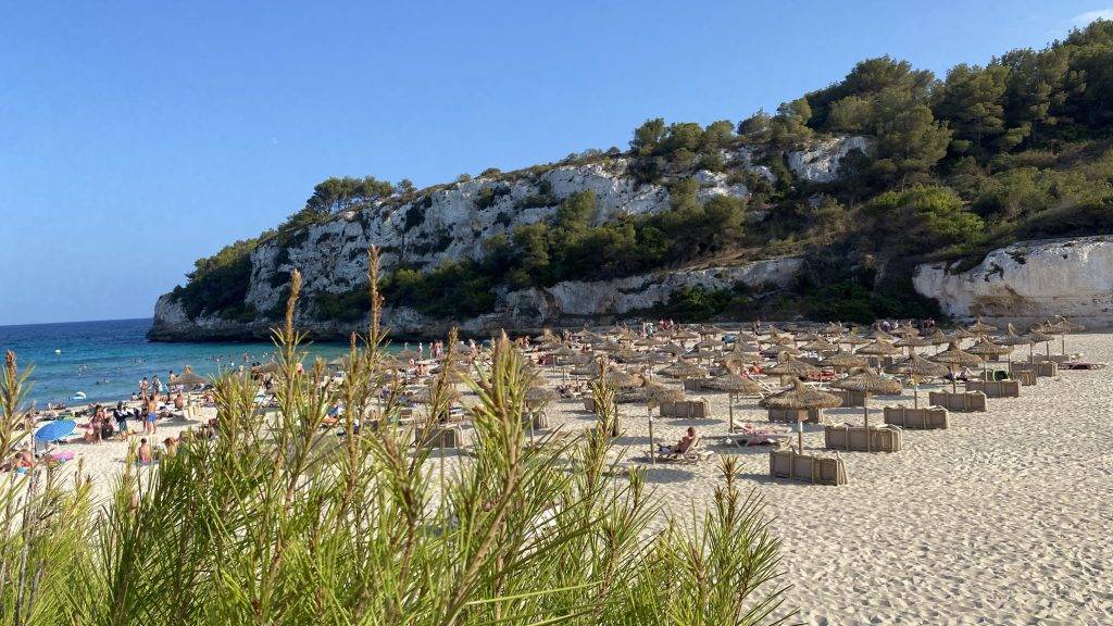leicht verdeckter Blick auf den breiten Sandtrand mit den Liegen direkt am Meer