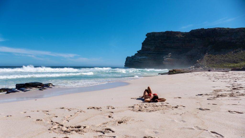 Sonnenbaden am Dias Strand mit Felsen im Hintergrund