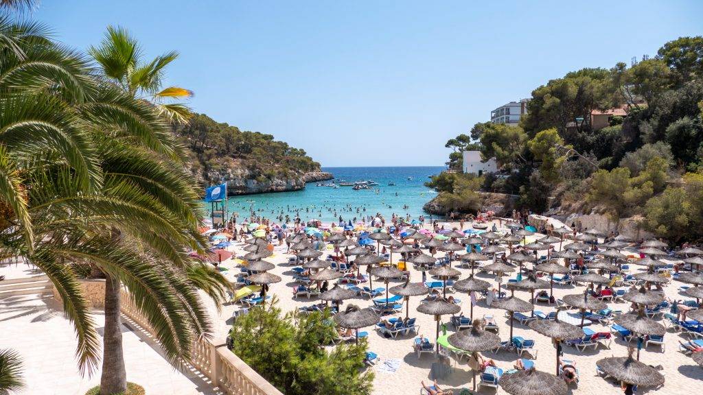 Aublick auf die Bucht von Cala Santanyi mit seinen unzähligen, bunten Sonnenschirmen