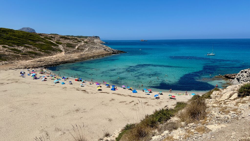 weiter Sandstrand mit bunten Sonnenschirmen vor dem türkisblauen Mittelmeer
