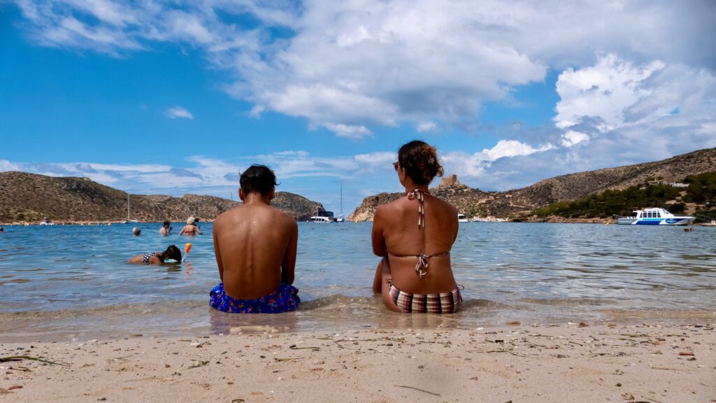 Im flachen Wasser direkt am Strand sitzend mit Blick auf die Bucht und den sanften Hügel