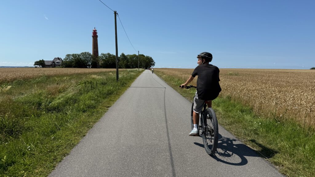 Radweg mitten in den Felder mit Fernsicht auf den Leuchtturm Flügge bei strahlend blauen Himmel
