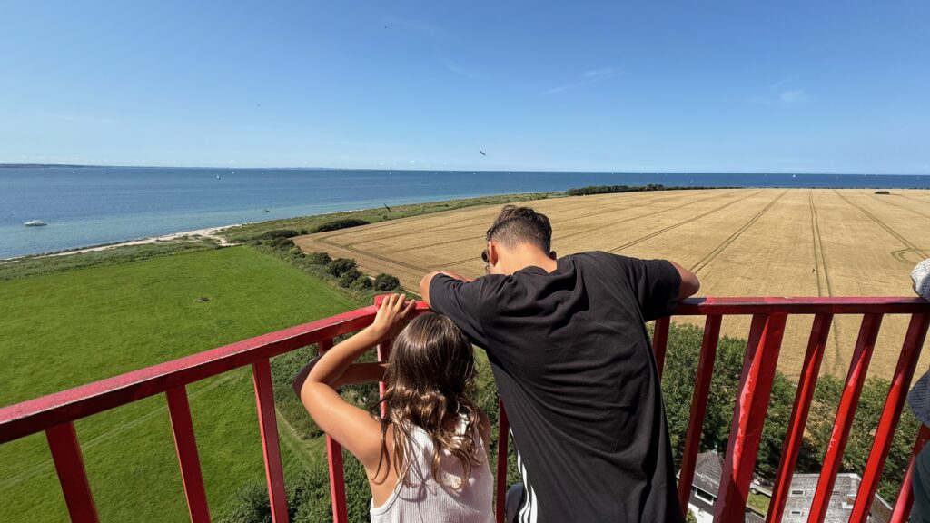 Leuchtturm Aussicht auf die umliegenden Felder mit der Ostsee im Hintergrund und strahlend blauem Himmel