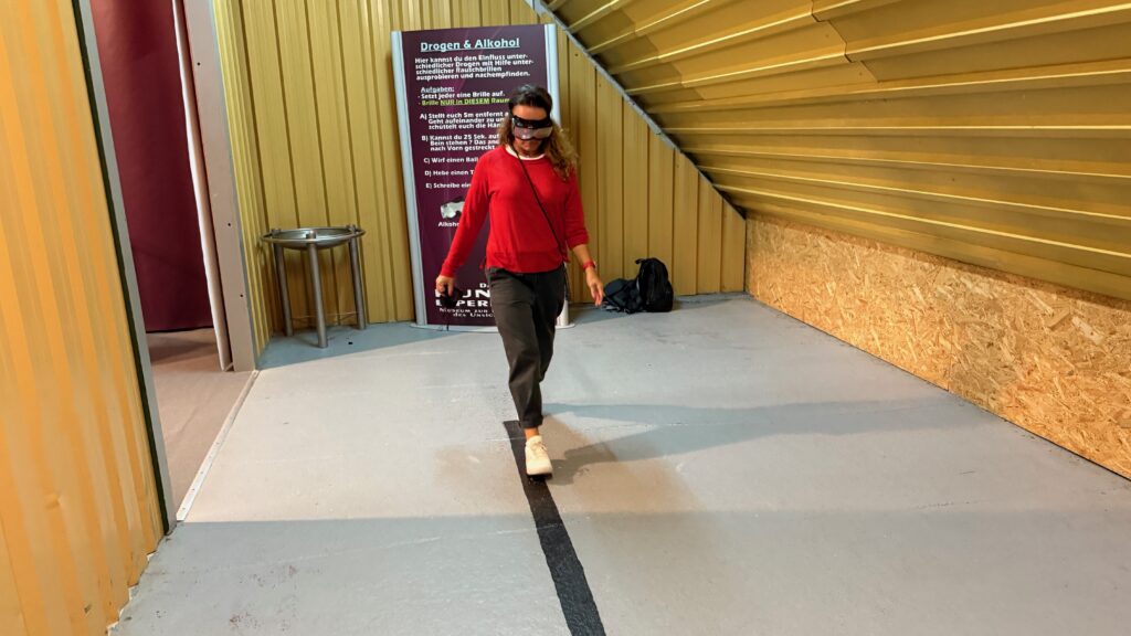 mit einer Drogenbrille auf einem schwarzen Strich entlanglaufen