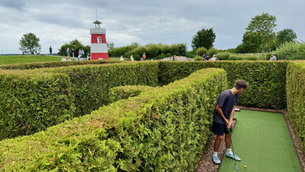 Labyrinth aus Hecken mit Kunstrasen für den Minigolf Parcours samt rot-weißen Holz Leuchtturm