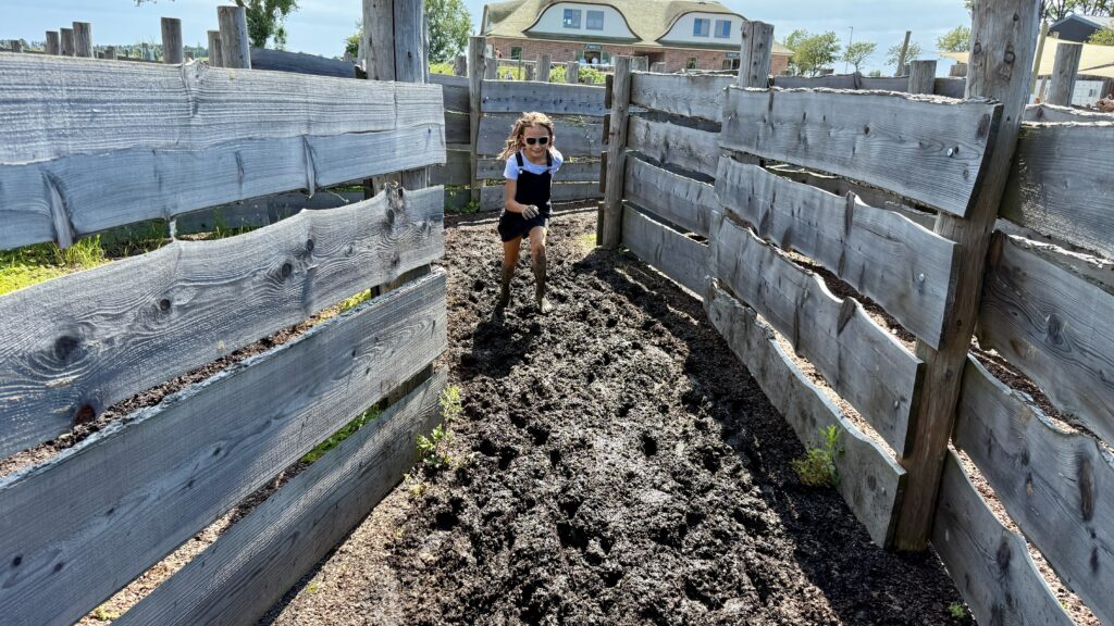 Matsche Labyrinth mit Holzplanken und Kinder die Matsche Füßen durch die Gänge sausen