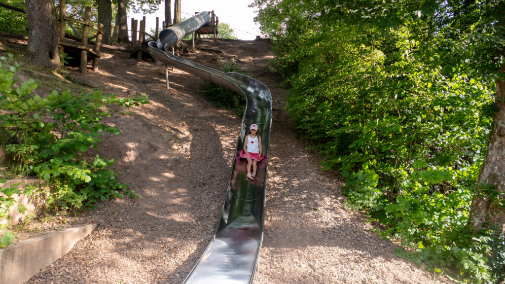 Kind rutscht die lange Edelstahlrutsche am Hang des Spielplatzes Räuberberg in Bad Wildbad hinunter