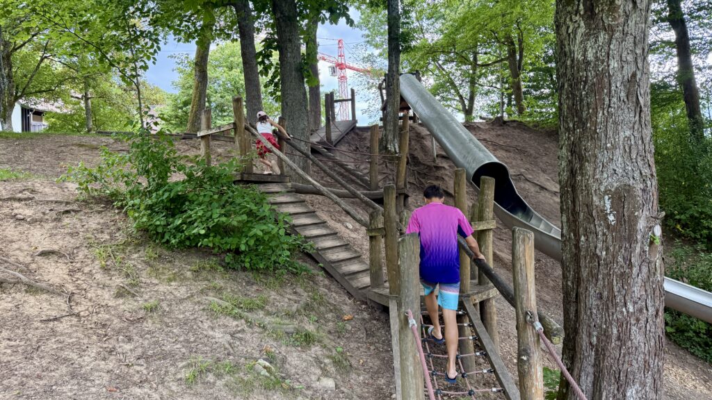 Kinder klettern über Holzrampe und Kletternetz zum Einstieg der Rutsche am Räuberberg in Bad Wildbad