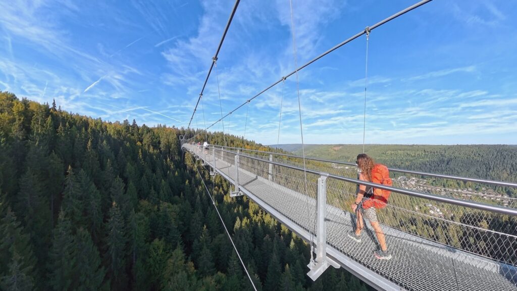 Frau mit rotem Rucksack auf der Hängebrücke Wildline in Bad Wildbad über dem Schwarzwald